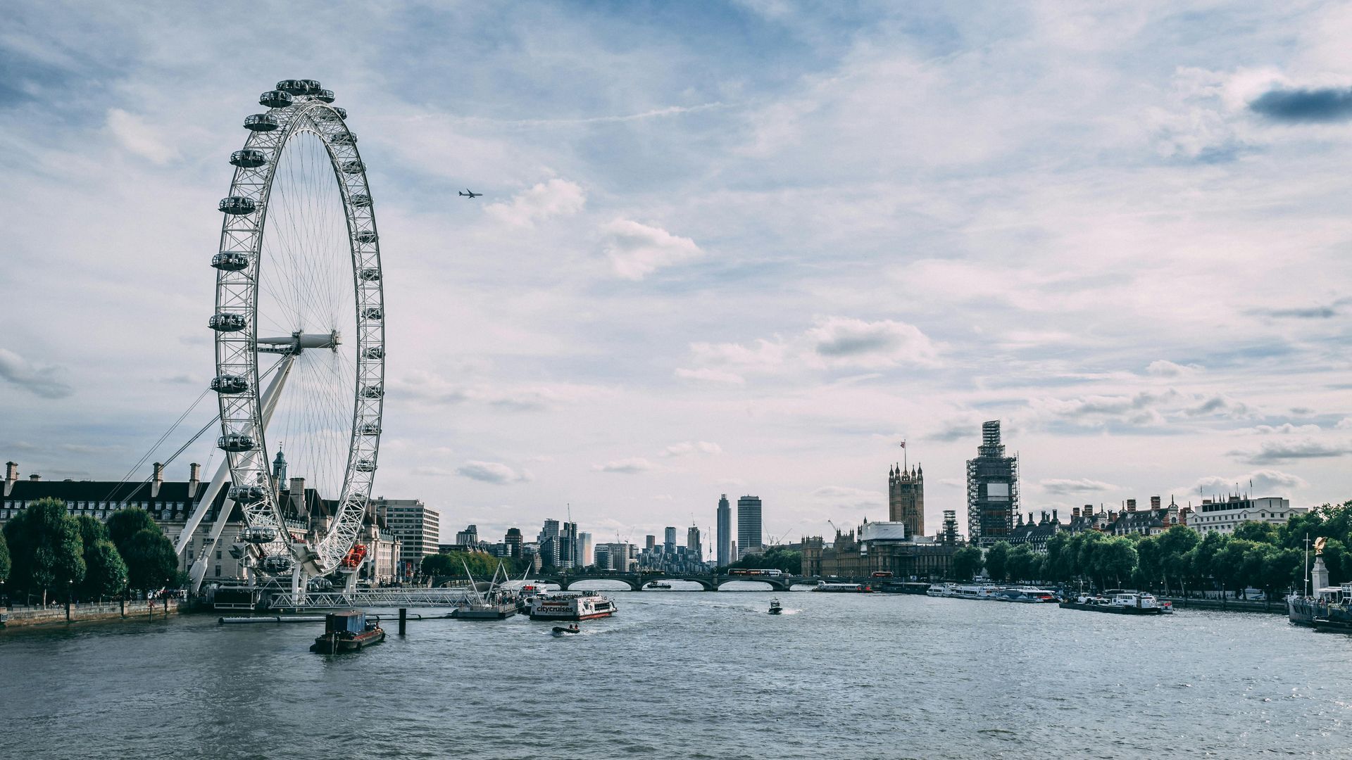 A ferris wheel is in the middle of a river in london.