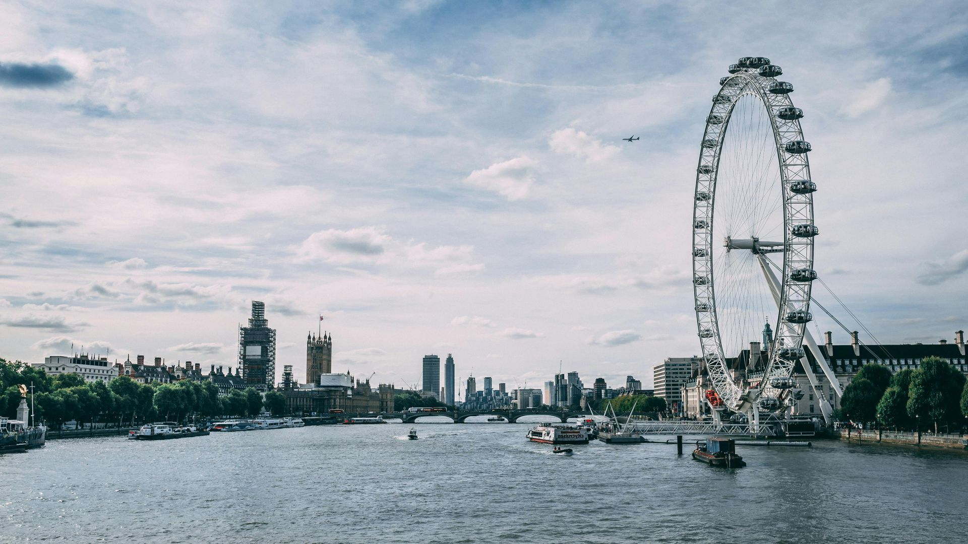 A large ferris wheel is in the middle of a river in london.