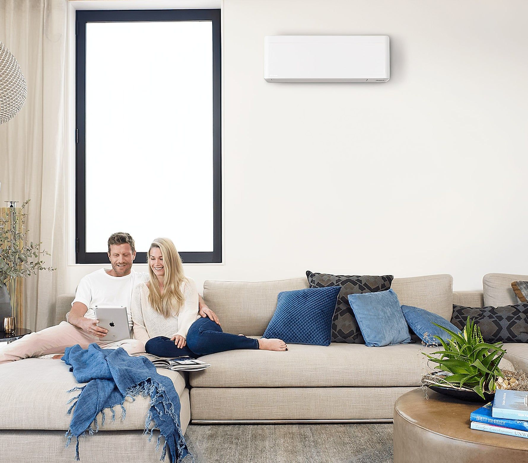 A man and a woman are sitting on a couch looking at a tablet.