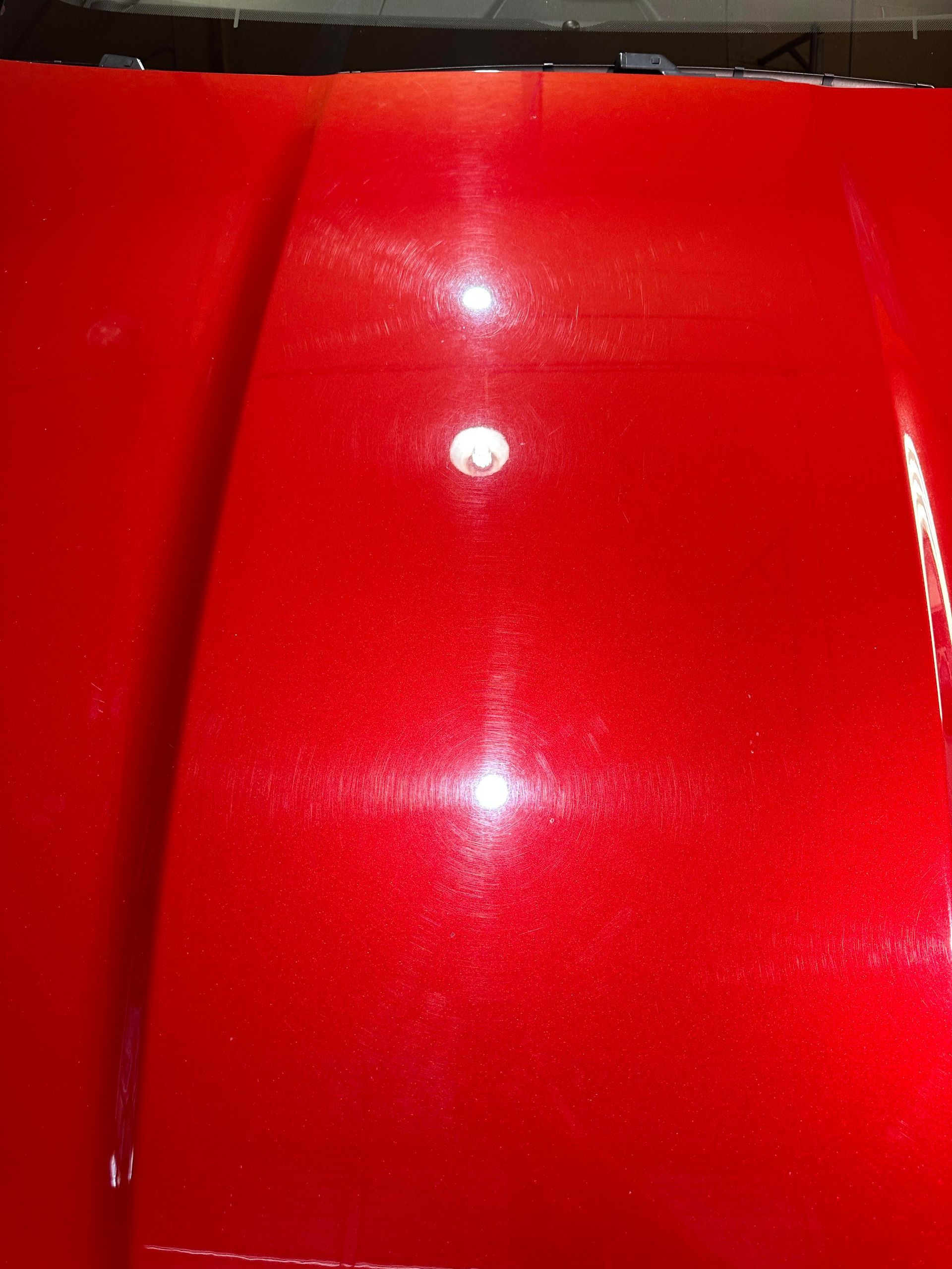 a close up of a red car hood with a light shining through it .