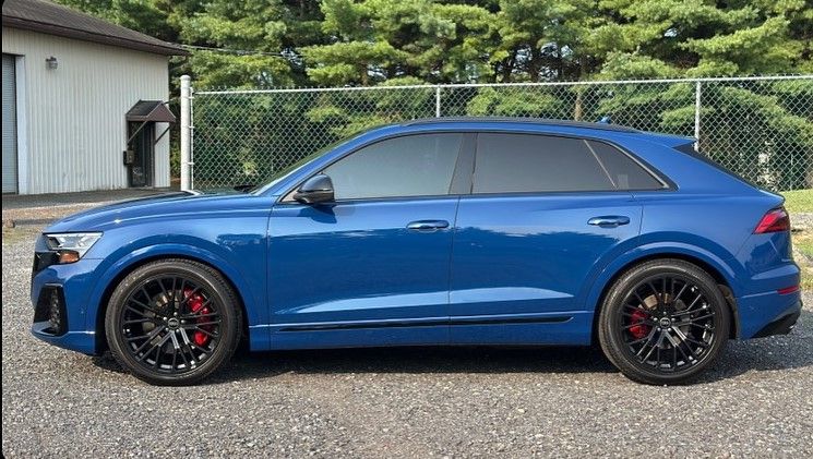 Blue Audi Q8 SUV with black rims and tinted windows parked outdoors.