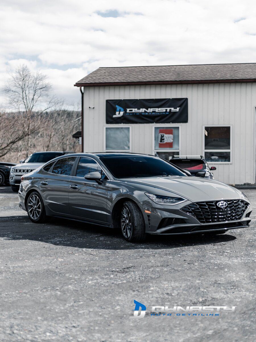 a gray hyundai sonata is parked in front of a building .