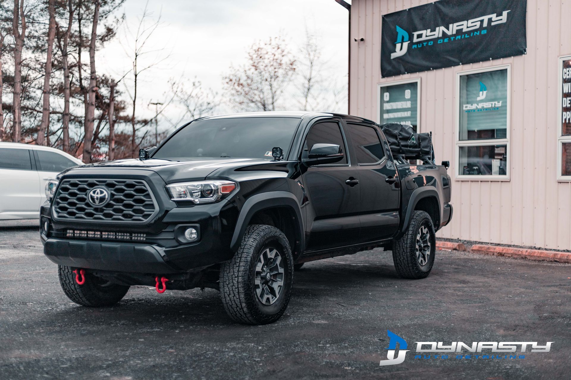 A black toyota tacoma is parked in front of a building.