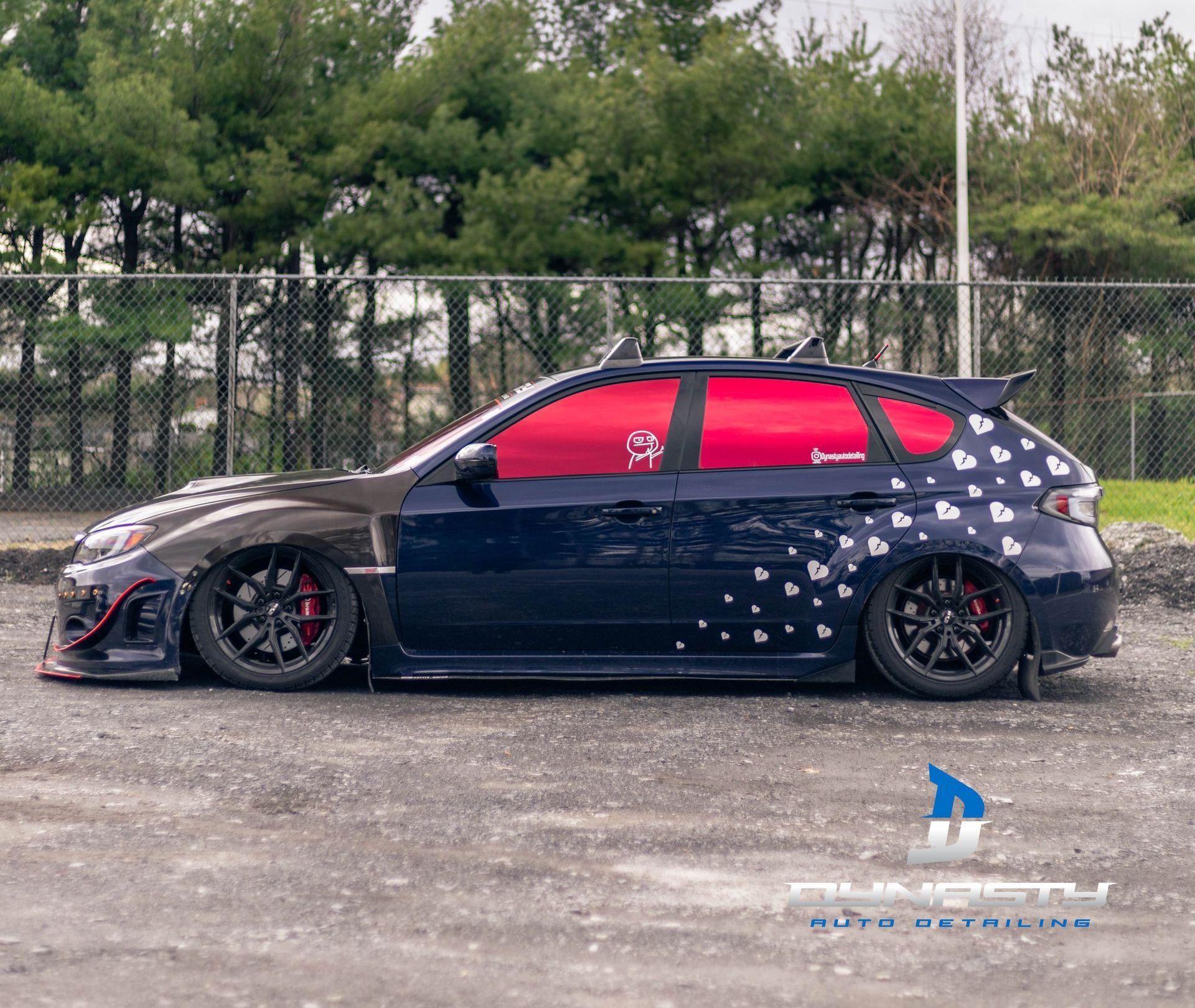 A black car with red windows is parked in a parking lot.