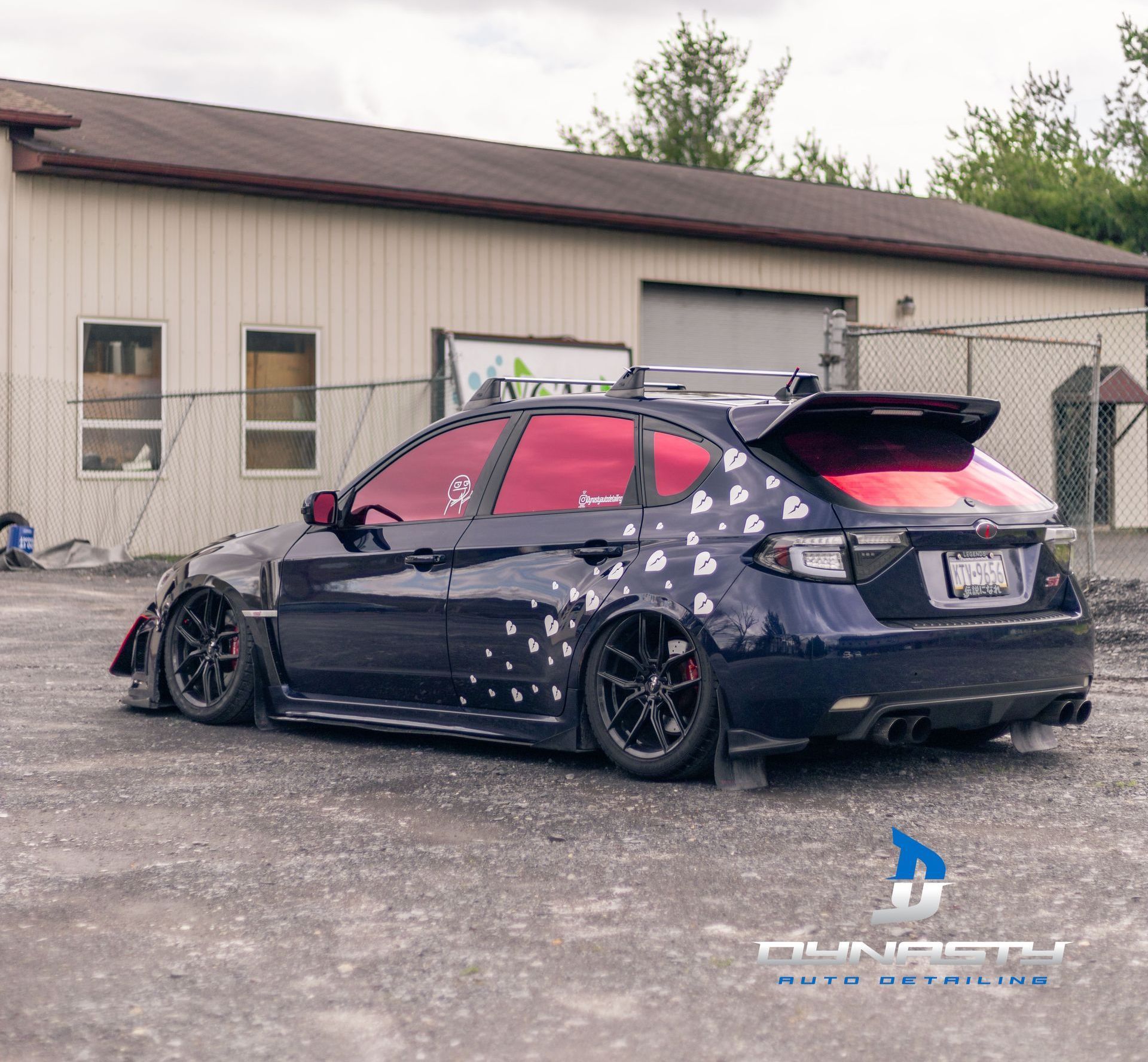 A car with a spoiler on the back is parked in front of a building.
