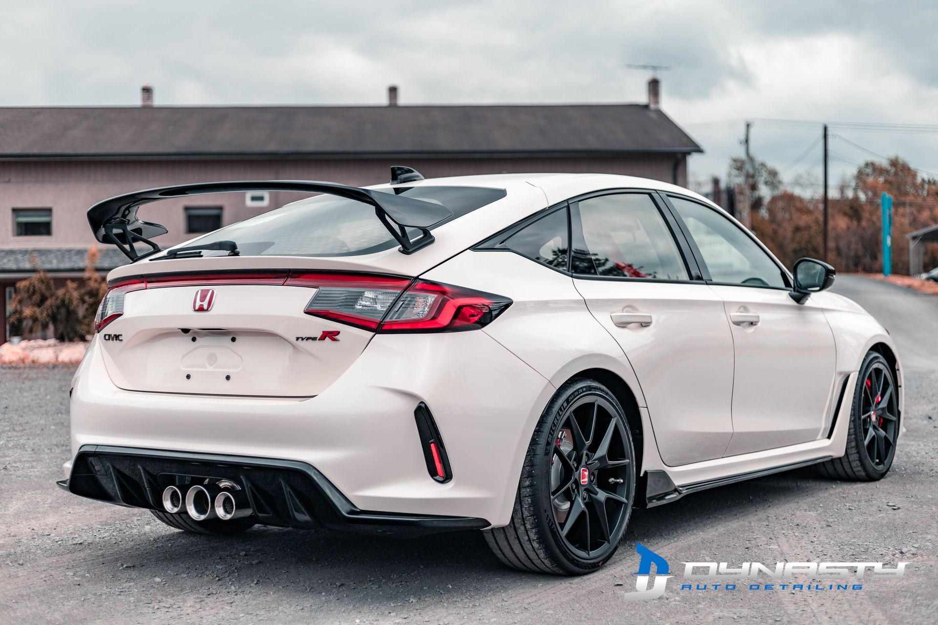 A white honda civic type r is parked in a parking lot in front of a building.