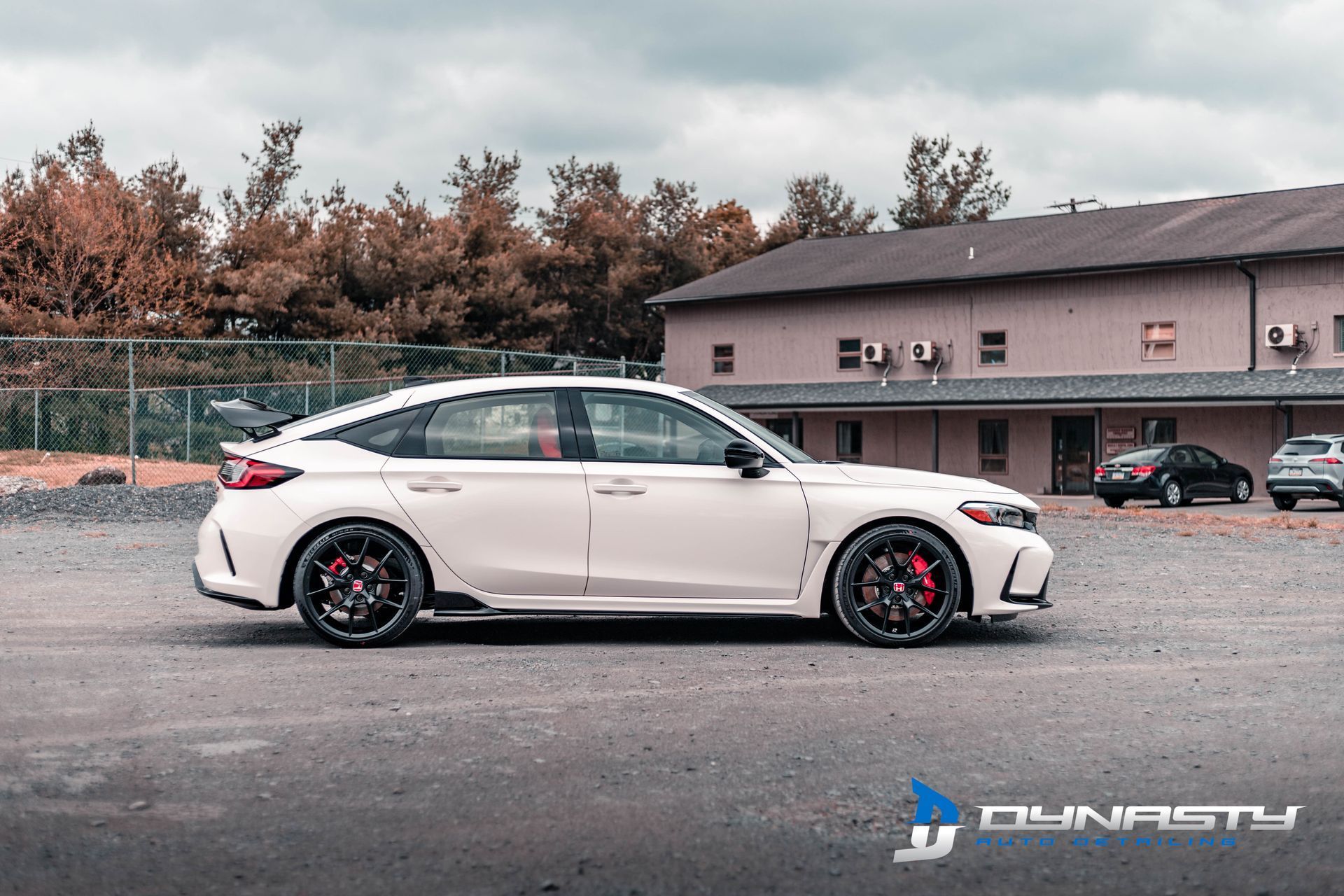 A white car is parked in a parking lot in front of a building.