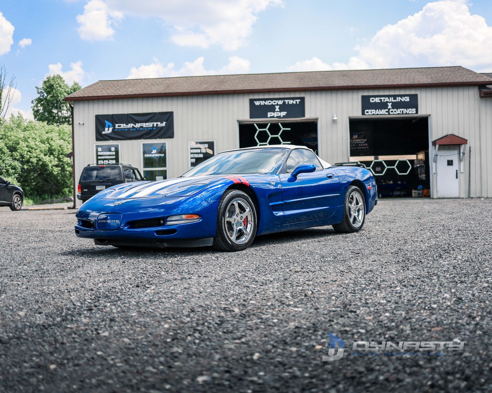 A blue corvette is parked in front of a garage.