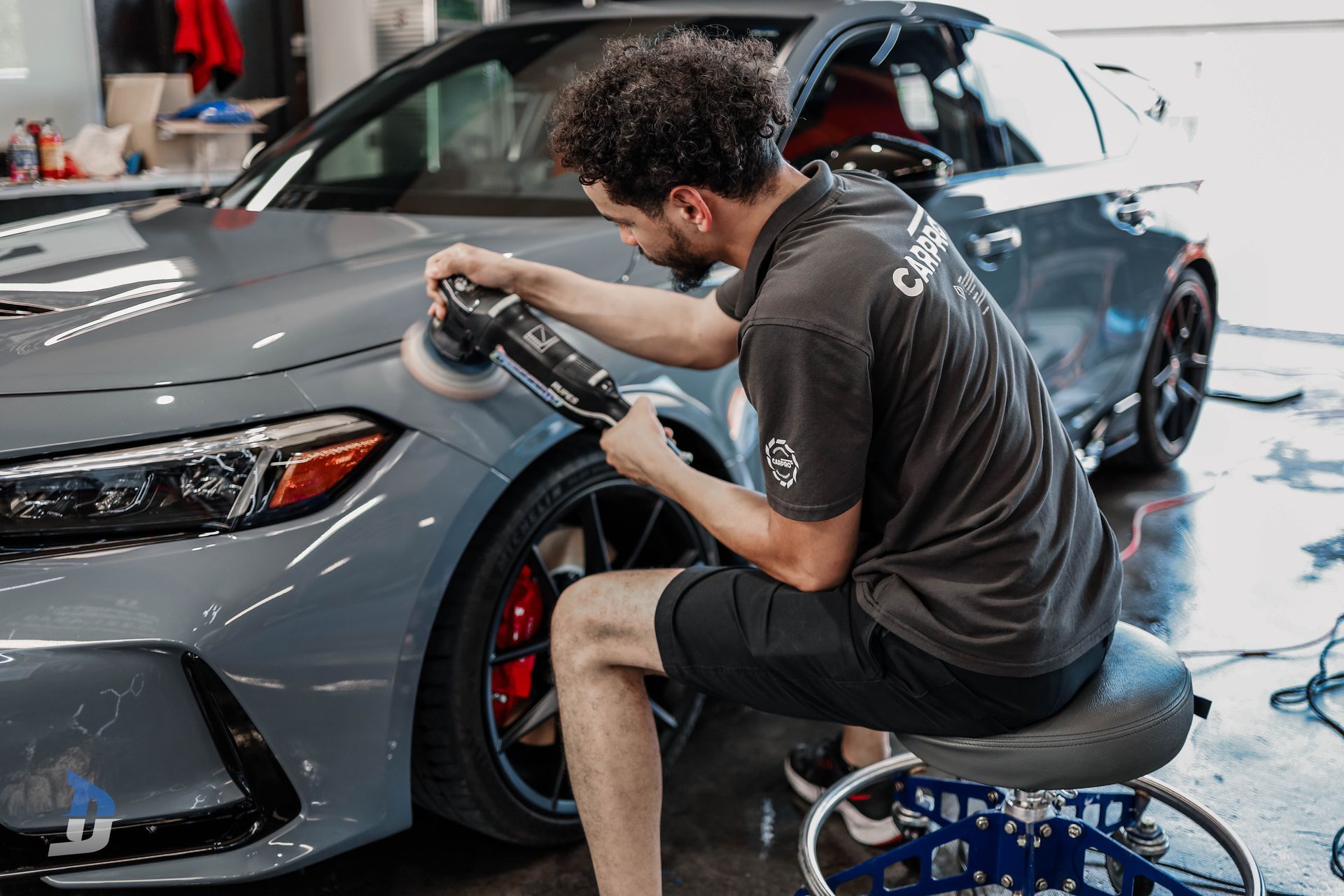 Detailing - A black sports car is parked in front of a garage.