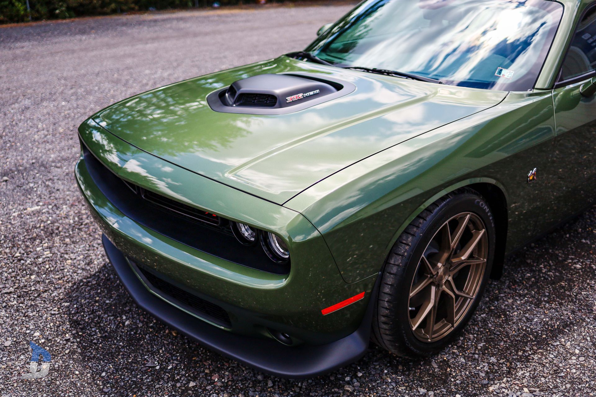 A green dodge challenger is parked on the side of the road.
