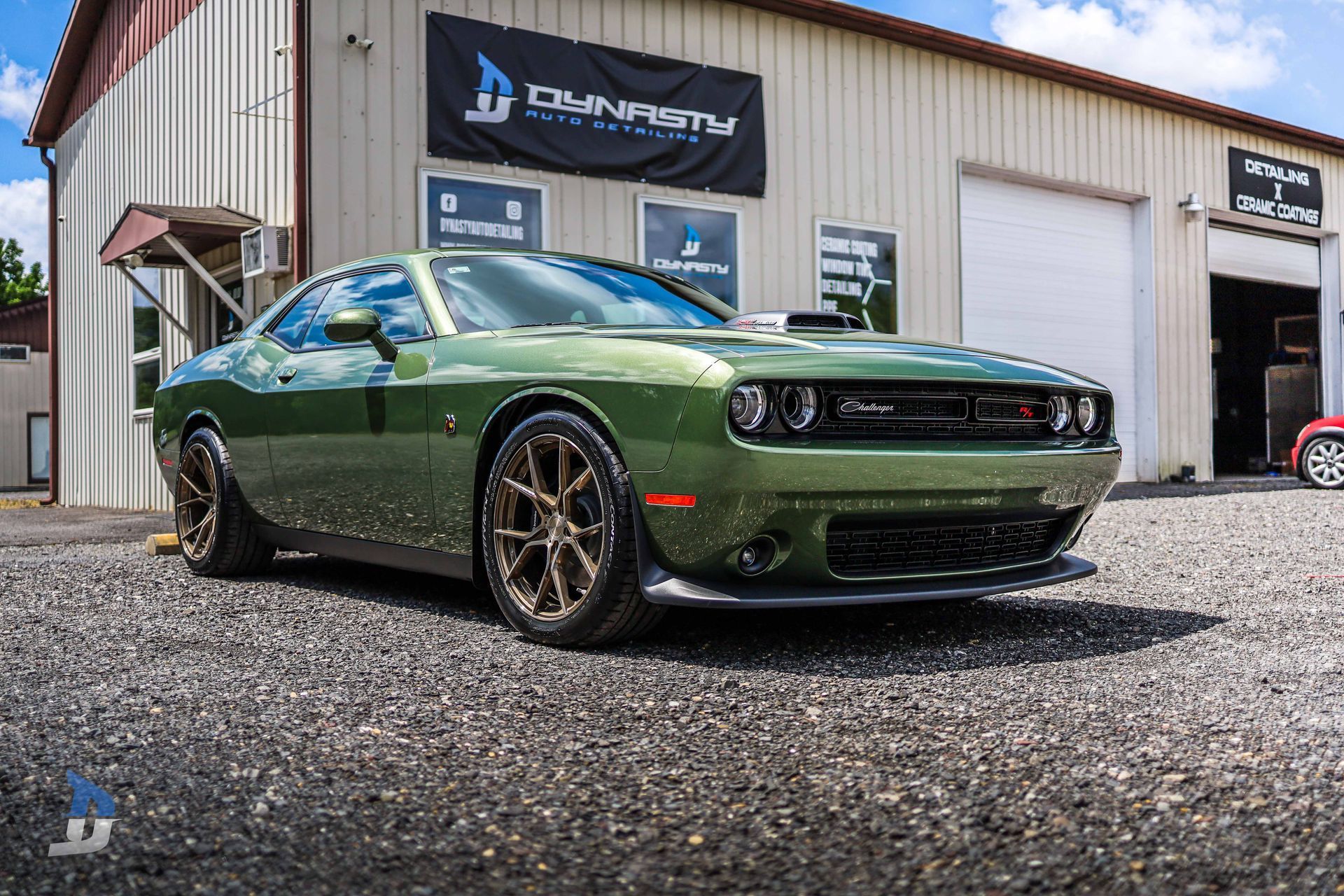 A green dodge challenger is parked in front of a building.