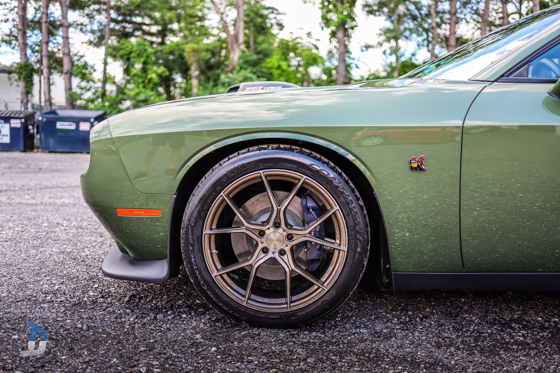 A green dodge challenger is parked on the side of the road.