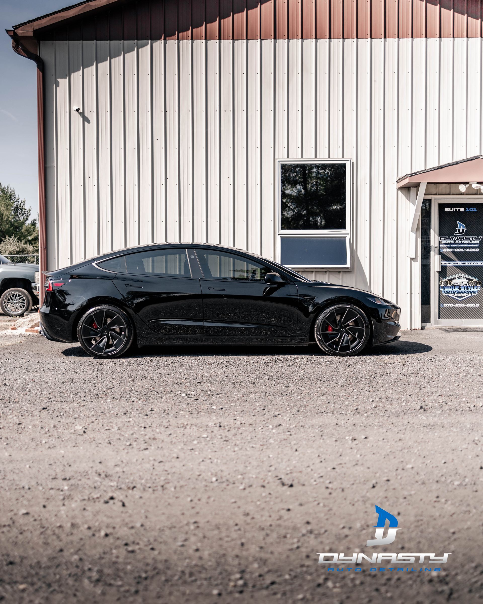 A black car is parked in front of a white building.