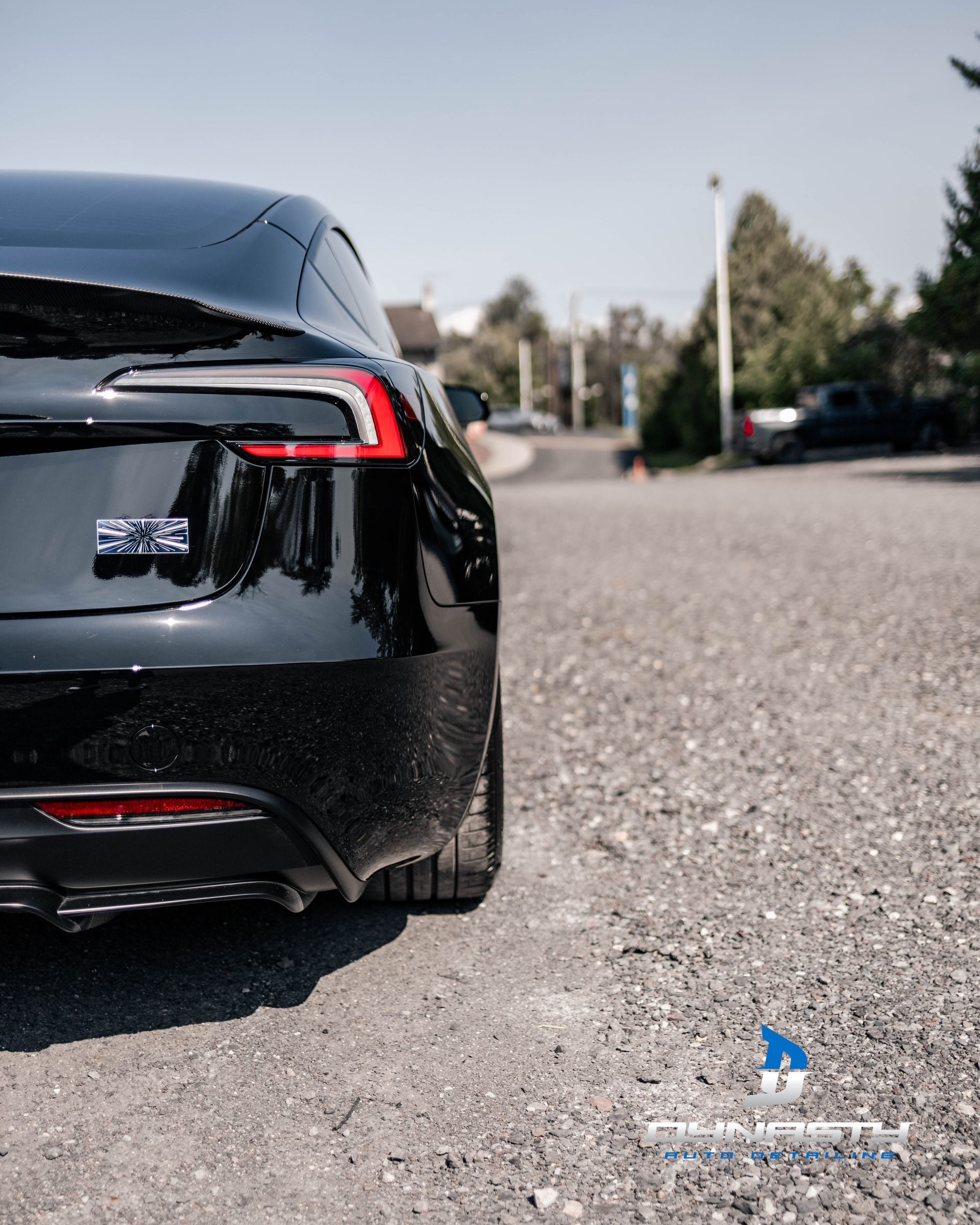 A black tesla model s is parked on a gravel road.