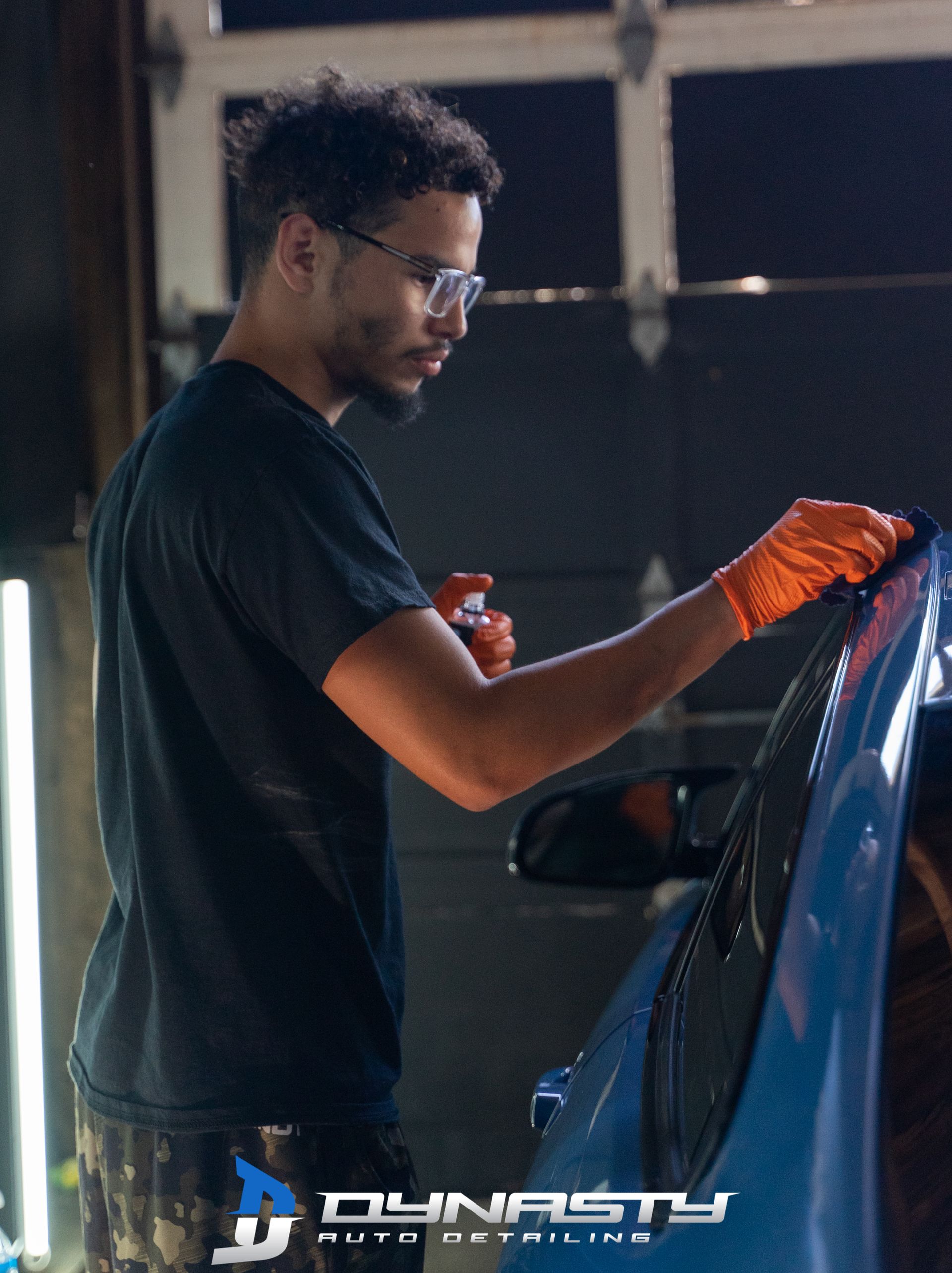Ceramic Coating - A man in a black shirt is polishing a blue car
