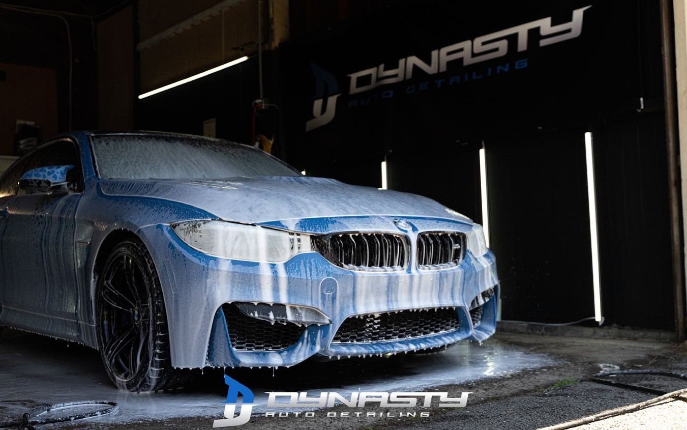 Ceramic Coating - A blue BMW M3 is covered in foam in a garage.