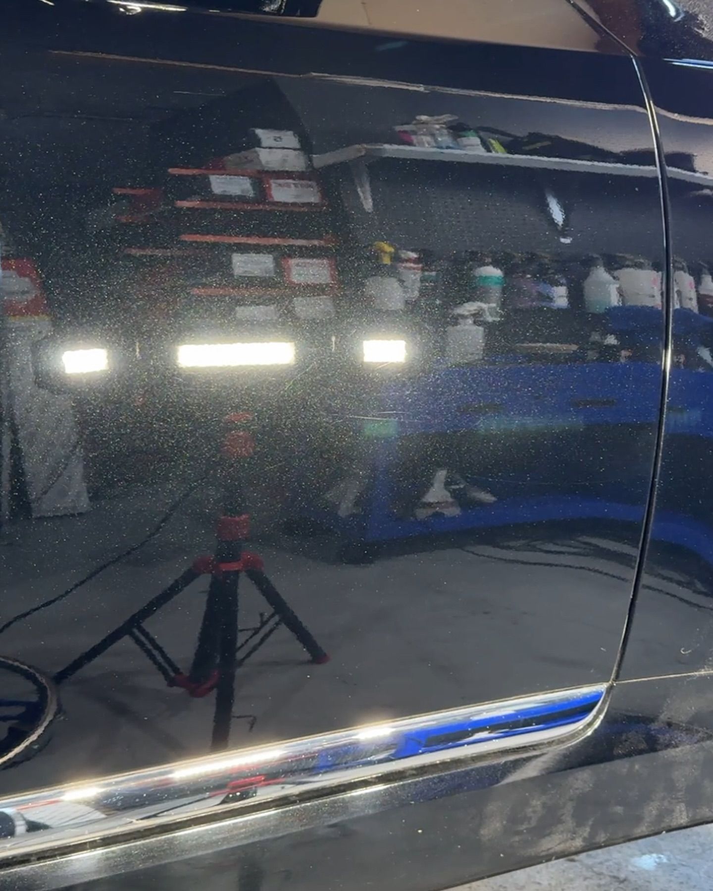 A black car is being polished in a garage