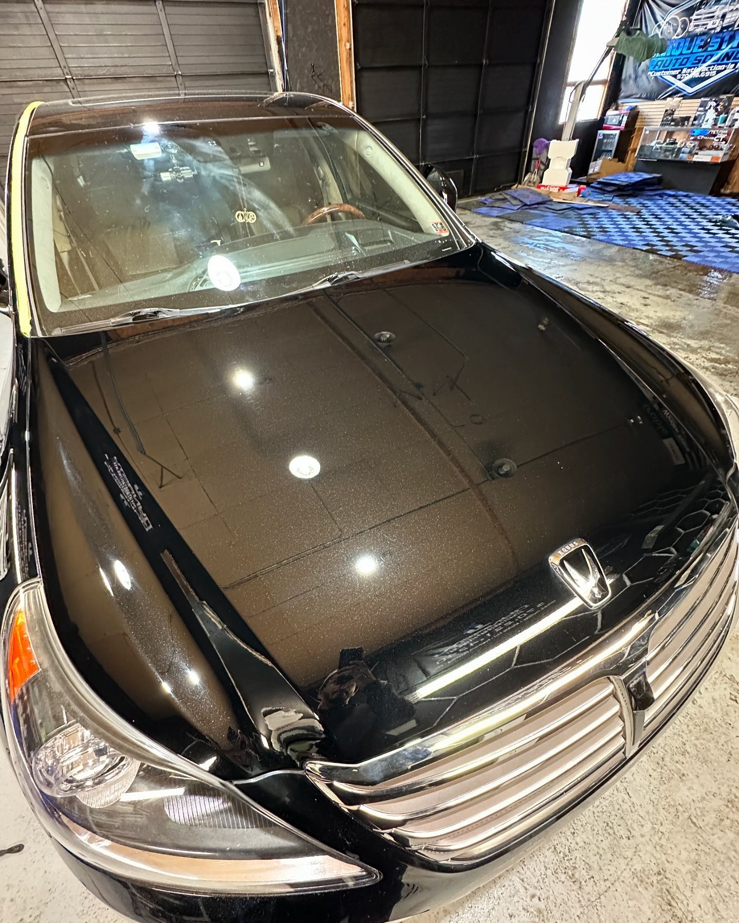 A black car is parked in a garage next to a garage door.