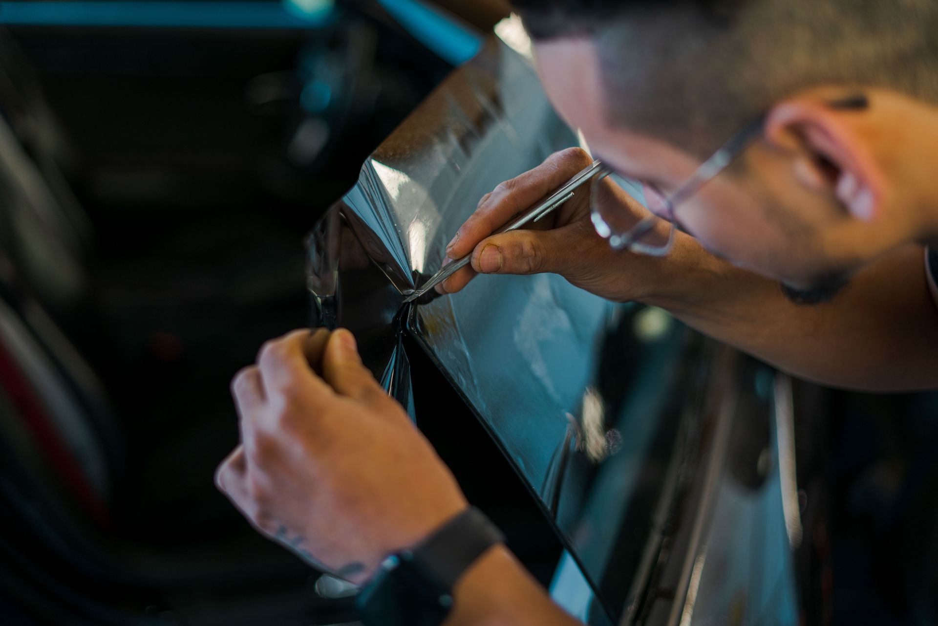 Window Tinting - A man is working on a car window with a pen.