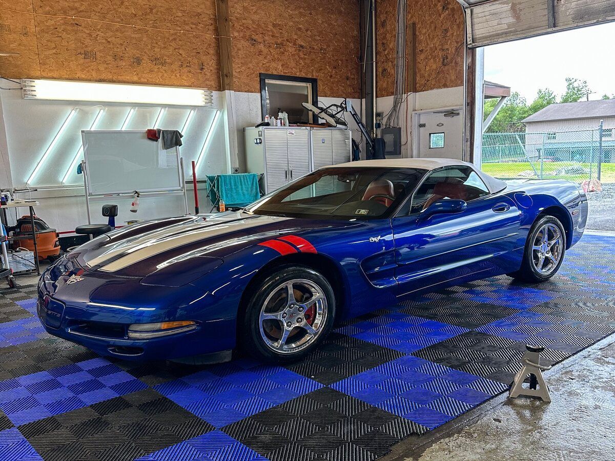 A blue corvette is parked in a garage.