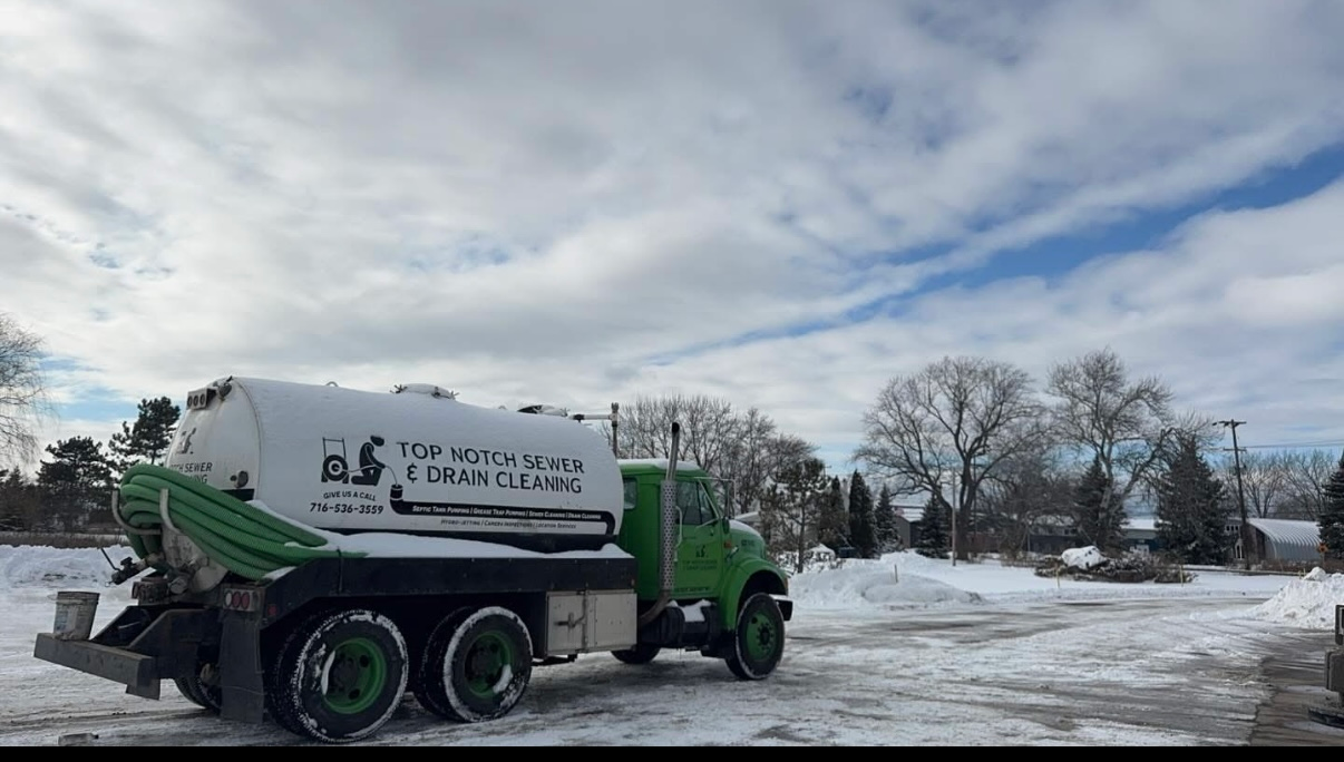 A green and white truck is parked in the snow.