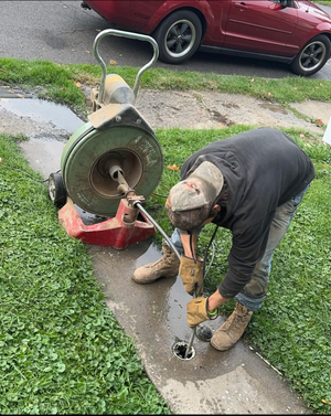 A man is working on a drain with a machine.