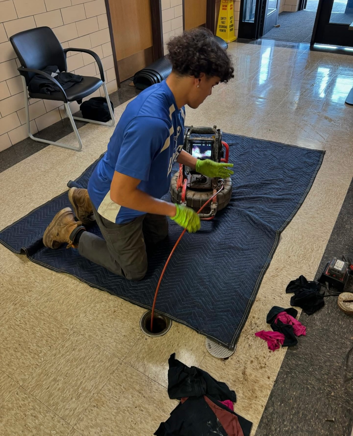 A man is kneeling on the floor using a machine.