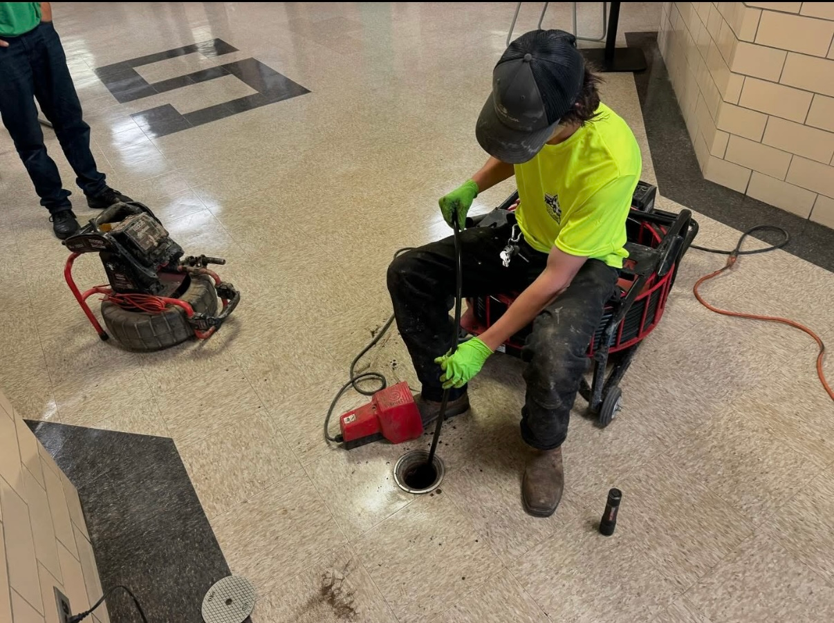 A man is sitting on a chair using a machine to fix a hole in the floor.