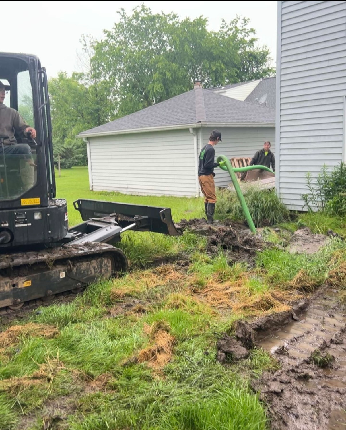 A man is standing next to a bulldozer in a muddy yard.