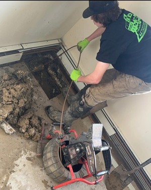 A man is working on a drain with a hose and a camera.