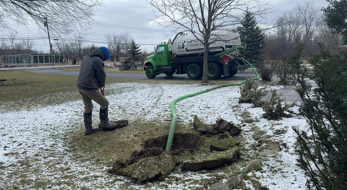 A man is standing in front of a green septic tank truck.