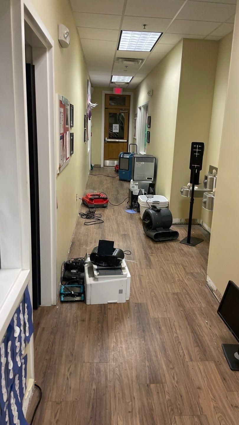 A narrow, cluttered hallway with light-colored walls