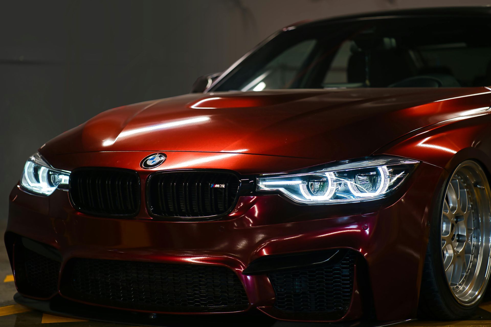 Red BMW sports coupe with glowing headlights in a dark setting
