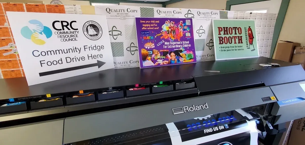 A printing machine with signs for a community food drive and photo booth.