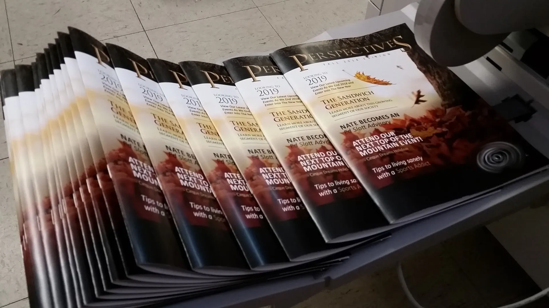 Stack of printed magazines with colorful covers, likely just printed.