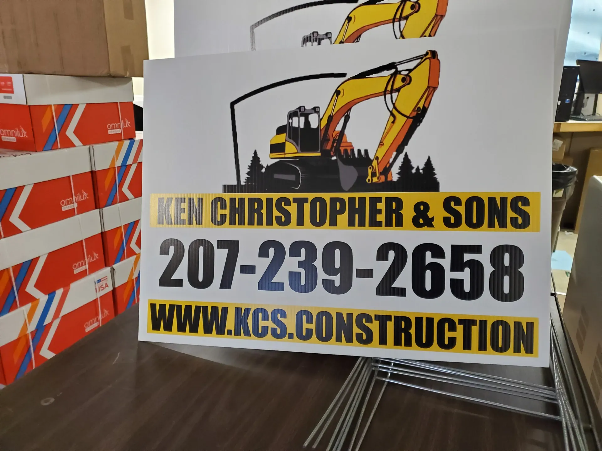 Construction sign for Ken Christopher & Sons: excavator graphic, phone number, website.