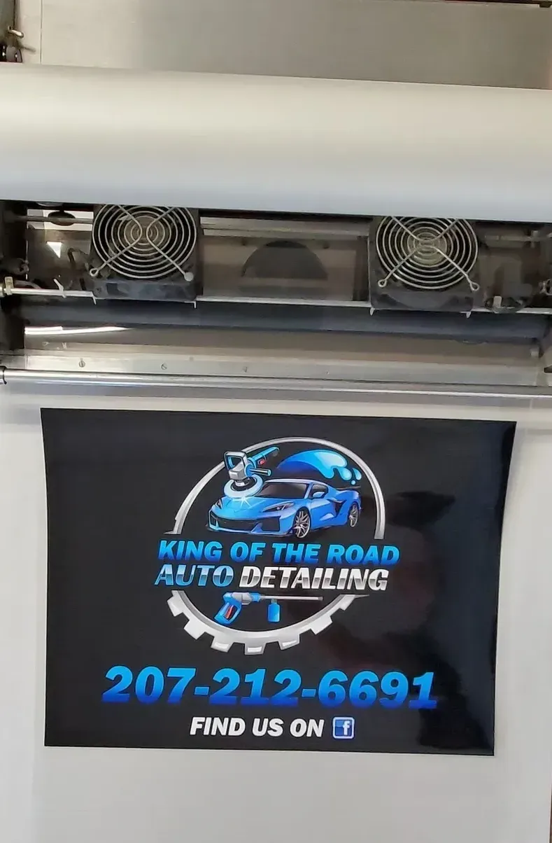 Sign for King of the Road Auto Detailing with a blue sports car graphic and phone number.