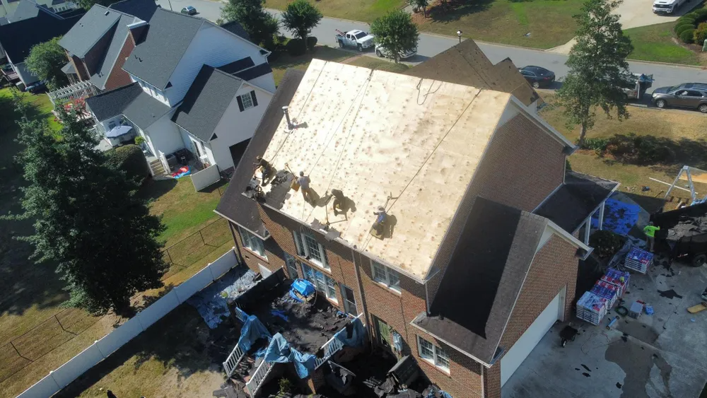 Roof under renovation with exposed wooden rafters and tools on a shingled roof