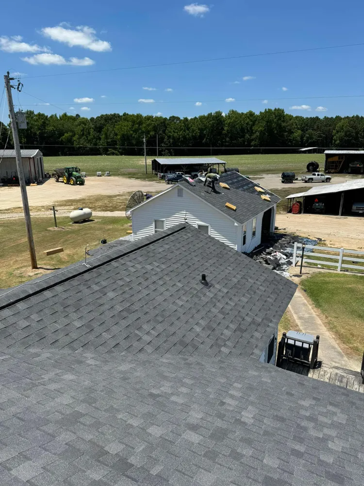 Roof under renovation with exposed wooden rafters and tools on a shingled roof