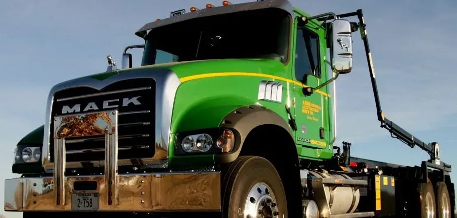 Green Mack truck with a silver front, against a light blue sky. Green Mack truck with a silver front, against a light blue sky.