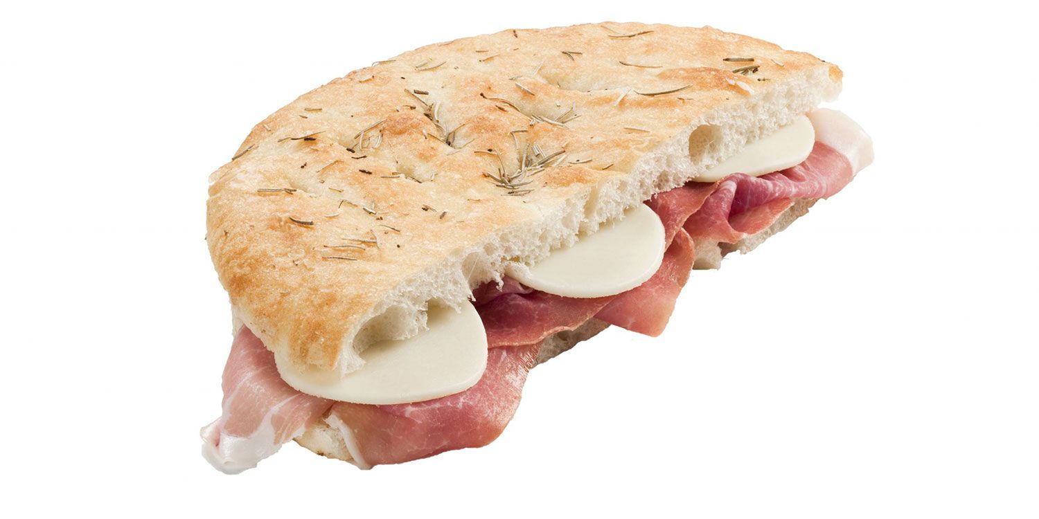 Primo piano di un panino con prosciutto e formaggio su sfondo bianco.