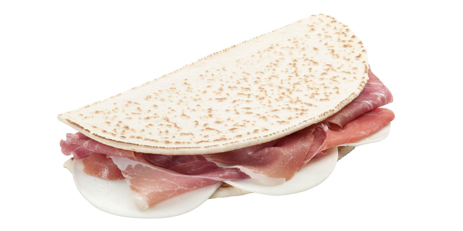 Primo piano di un panino con carne e formaggio su sfondo bianco.