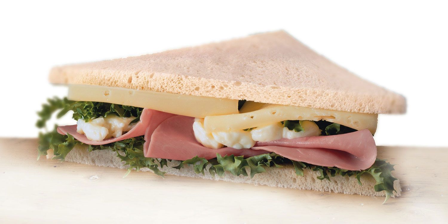 Un panino con prosciutto, formaggio e lattuga su una fetta di pane.