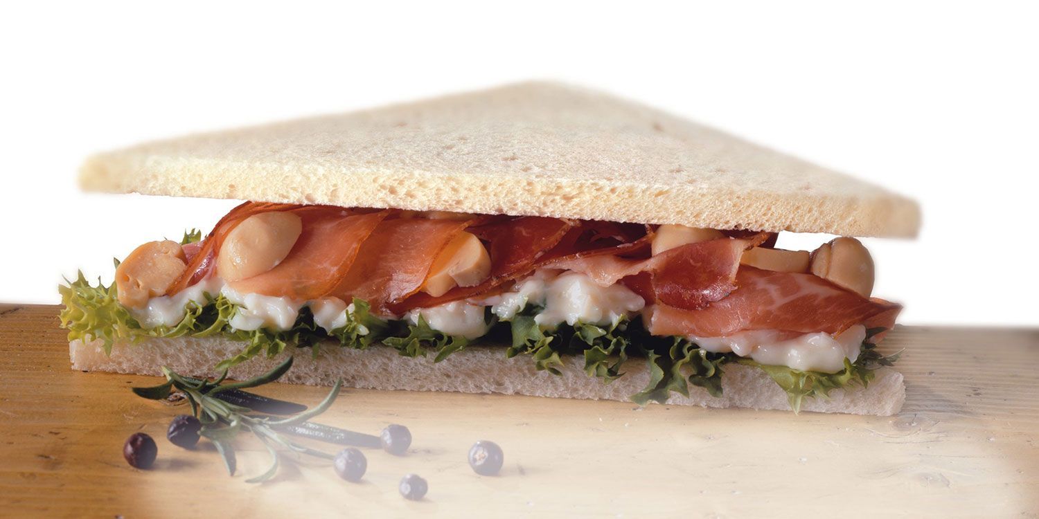 Un panino viene tagliato a metà su un tagliere di legno.