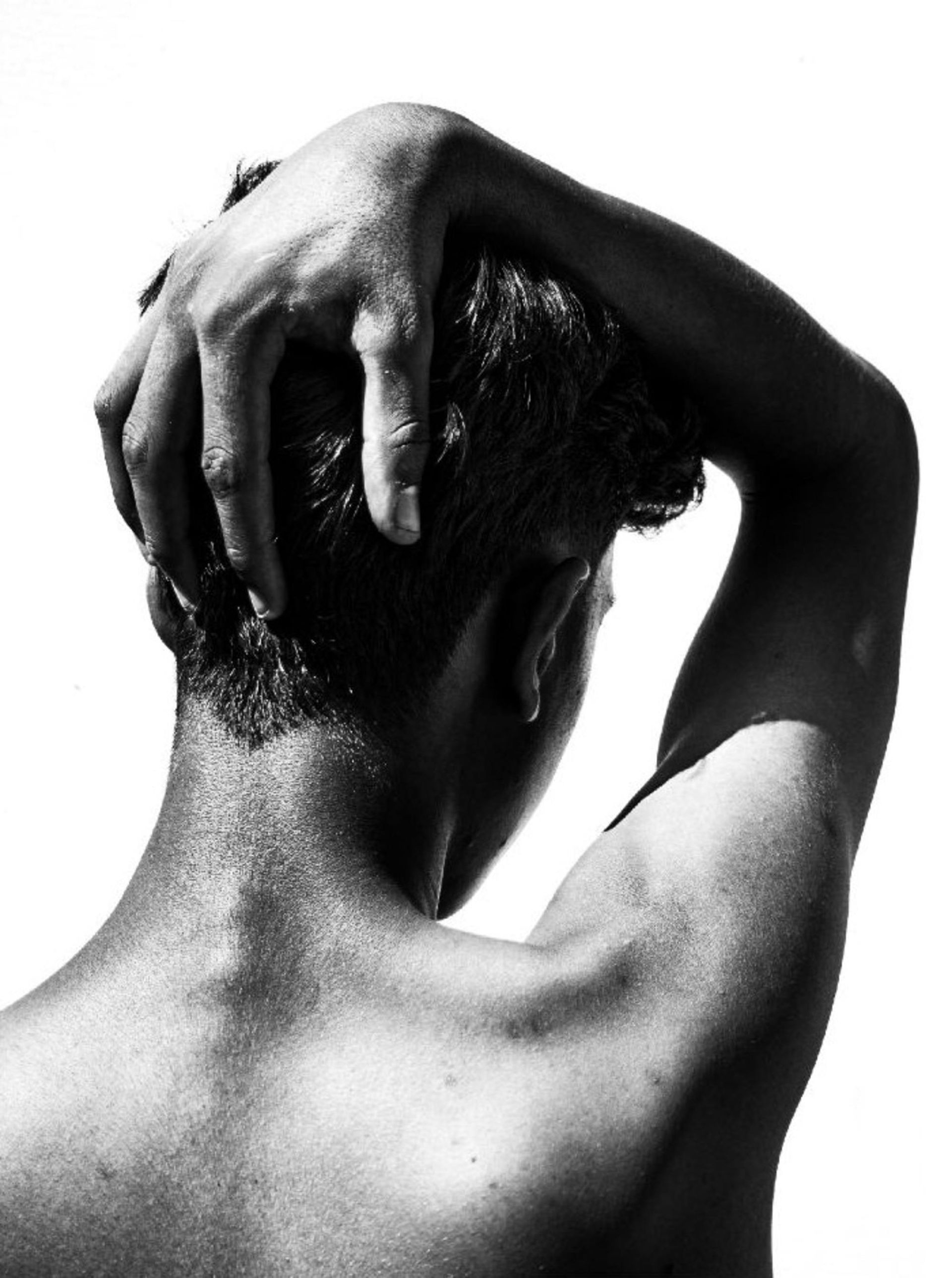 Back view of person with hand on head, in black and white.