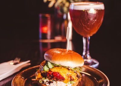 Cheeseburger on a plate with beer in a stemmed glass. Dark setting.