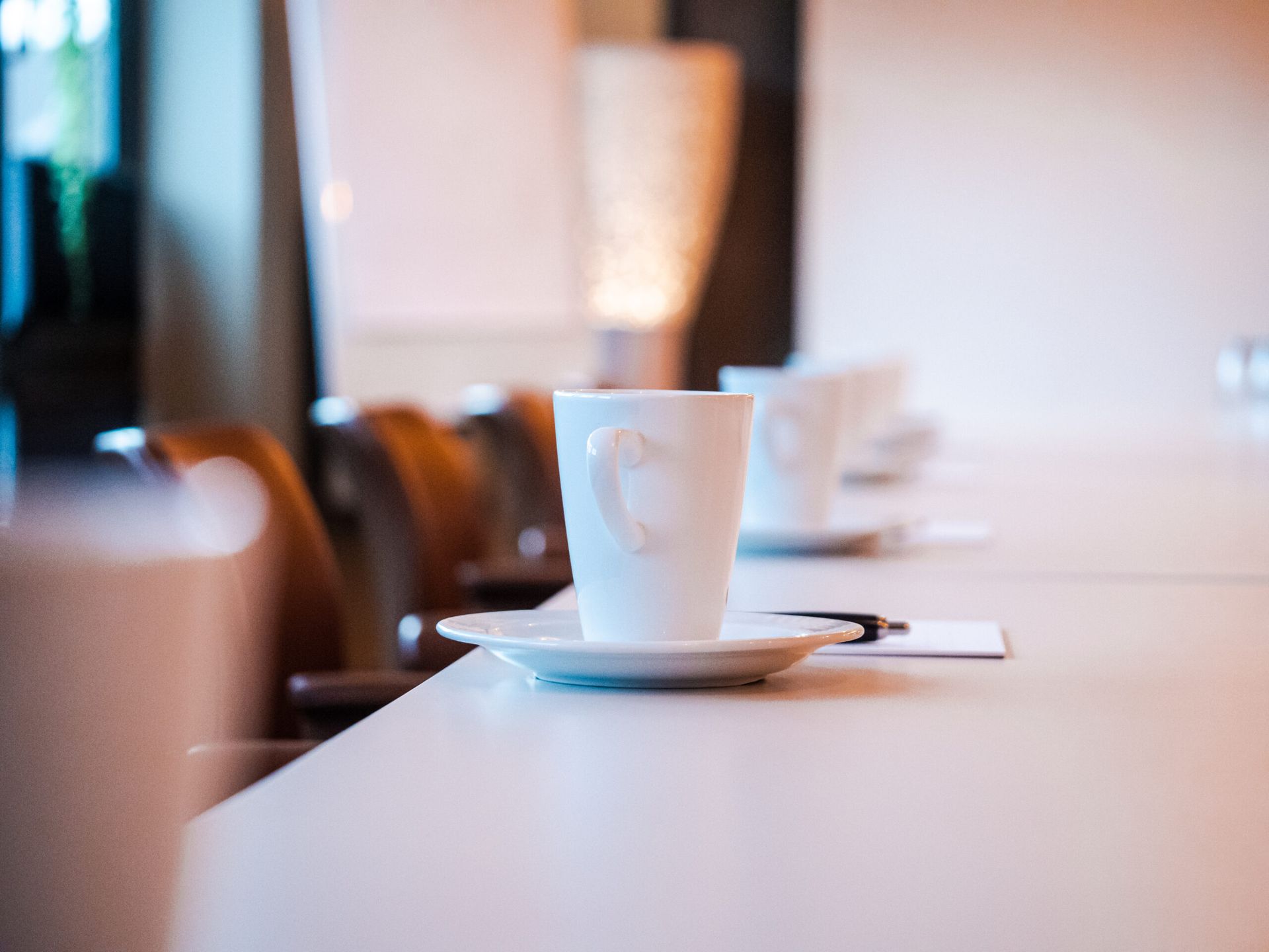 White teacup with a heart design on a saucer, on a white counter, blurred background.