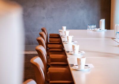 Conference table with brown chairs and white tableware set.
