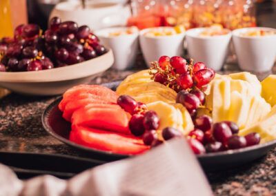 Fruit platter with watermelon, grapes, and pineapple; buffet setting.