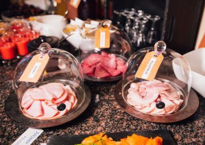 Buffet with sliced meats under glass domes, labels included.